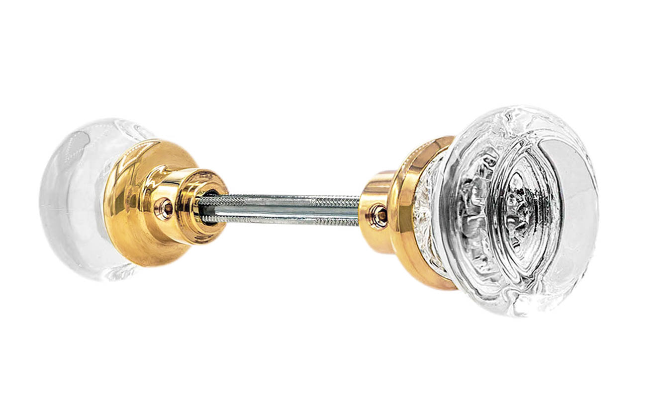 Pair of Classic Round Clear Glass Doorknobs with spindle. A high quality & genuine glass doorknob set with an attractive round design. The sparkling center point under glass amplifies reflected light to showcase beautiful facets. Solid brass base. Reproduction Glass Door Knobs. Traditional Round Glass Knobs. Unlacquered Brass (Will Patina Over Time). Non-Lacquered Brass.